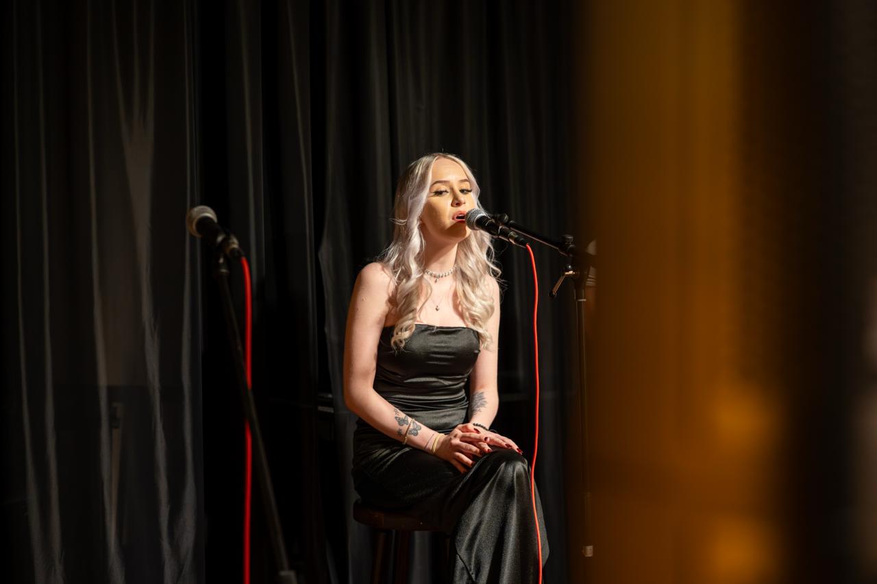 Sängerin im schwarzen Kleid auf der Karaoke-Bühne